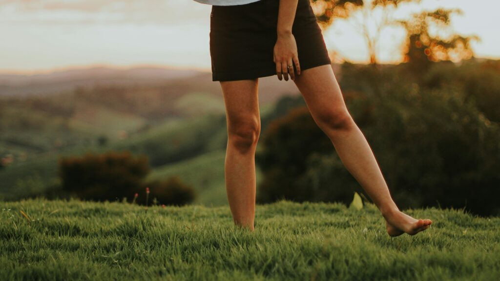woman in black shorts standing on green grass field during daytime