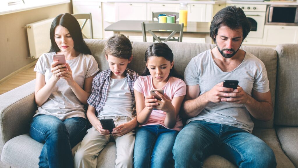 Concentrated members of family sit together on one sofa