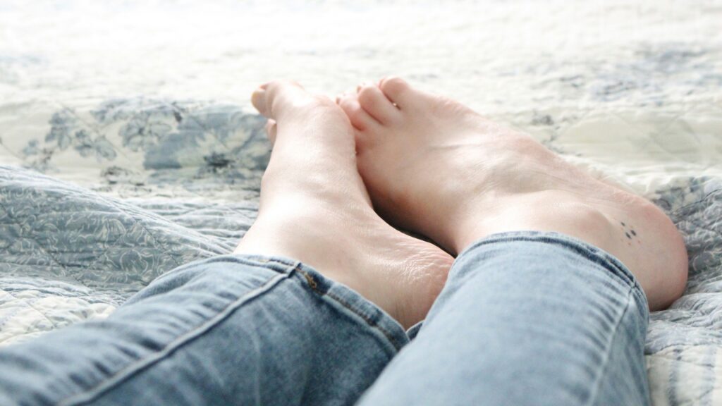 person in blue denim shorts lying on white sand during daytime