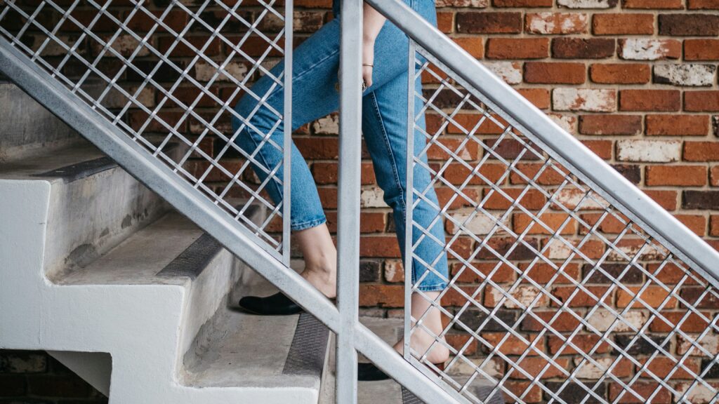 woman walking on stair near railling and wall