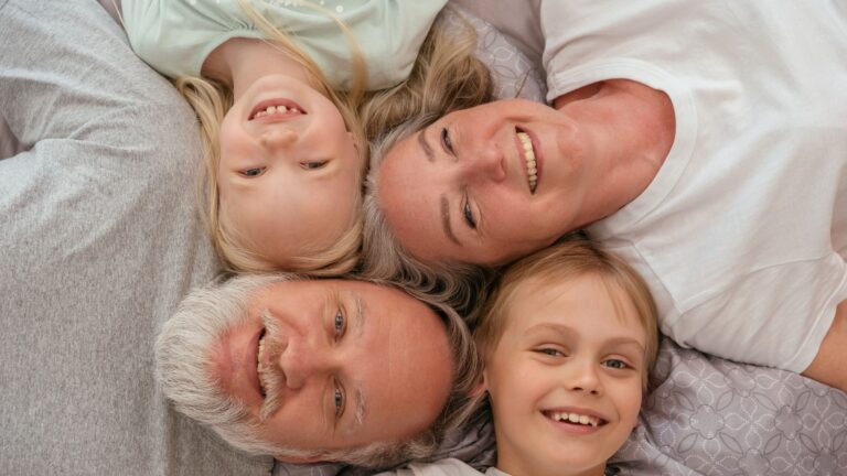 A joyful multigenerational family lying down and smiling together, displaying warmth and affection.