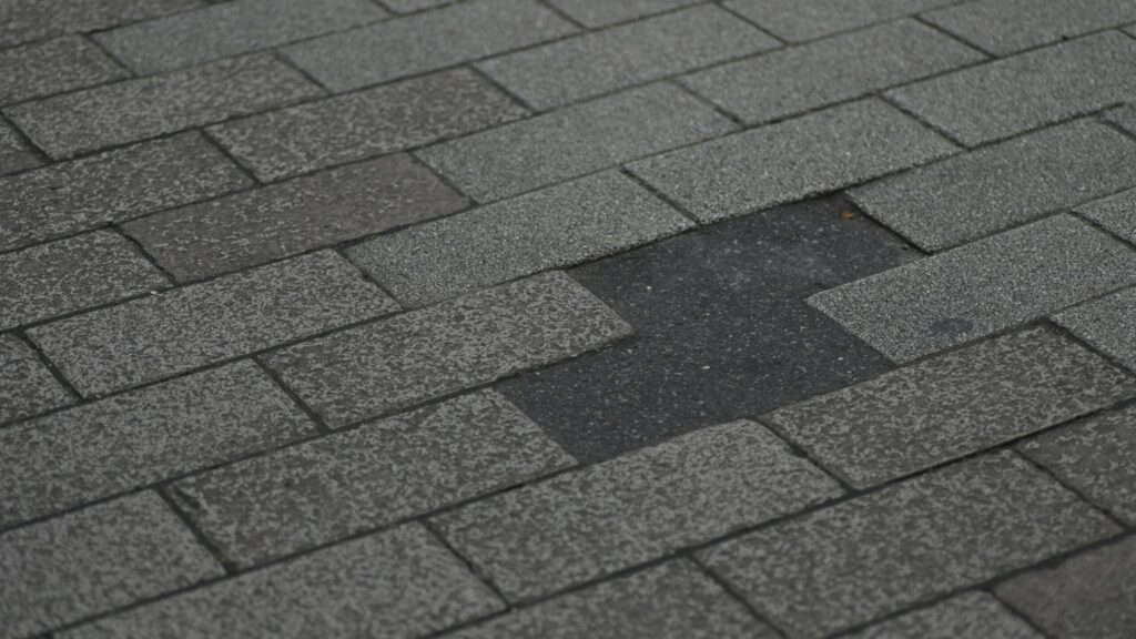 Damaged asphalt shingle roof with missing shingles.