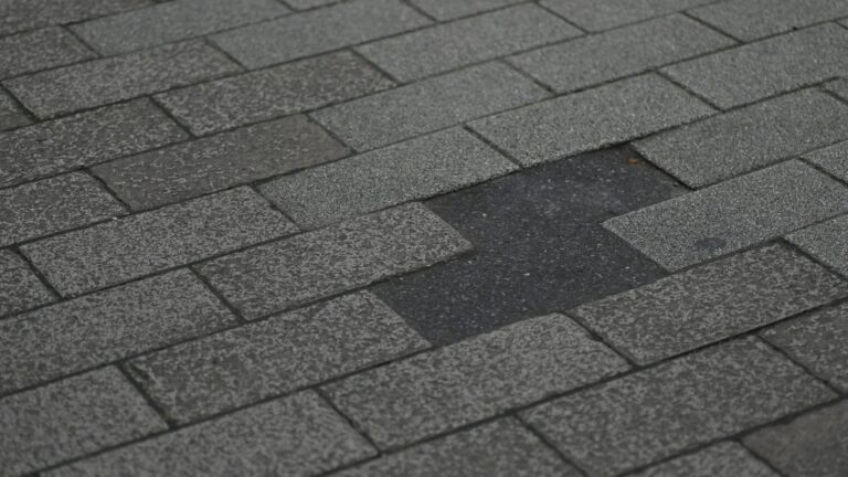Damaged asphalt shingle roof with missing shingles.