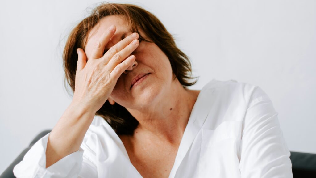 a woman sitting on a couch holding her hands to her face