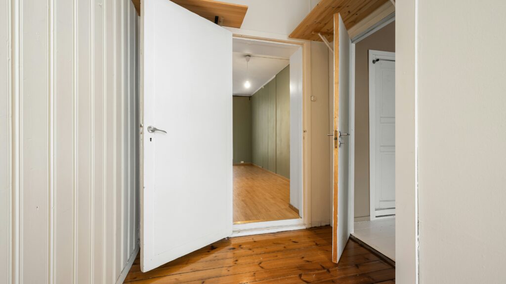 An empty room with a white door and a wooden floor