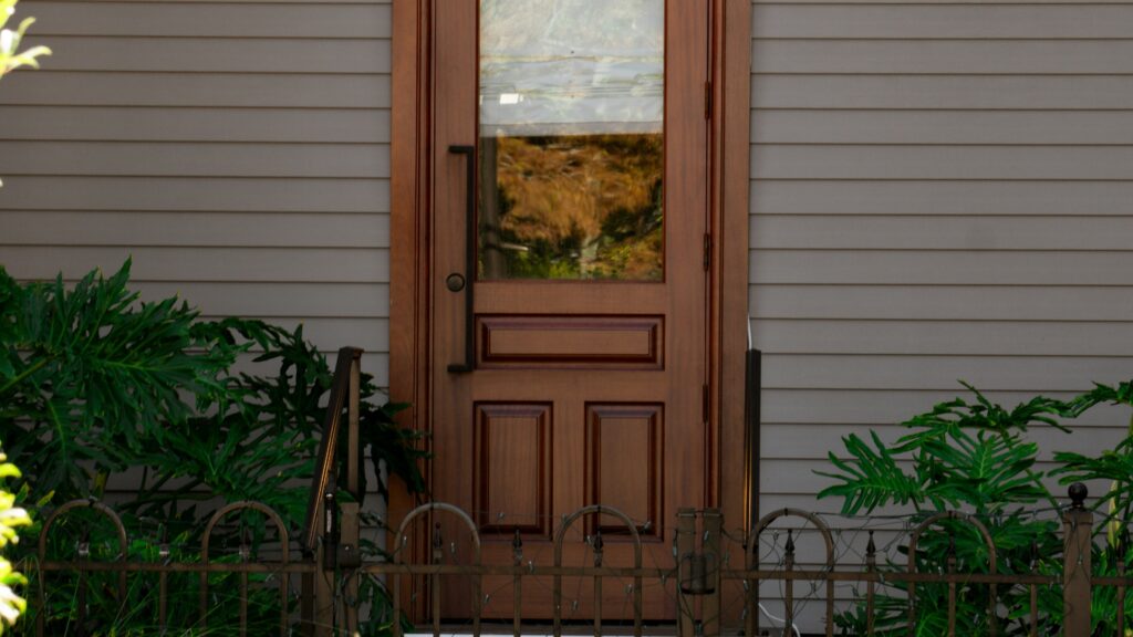A wooden door with glass panels and plants