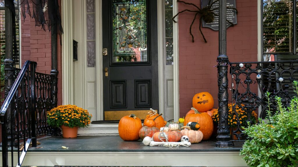 a front porch decorated for halloween with pumpkins and gourds