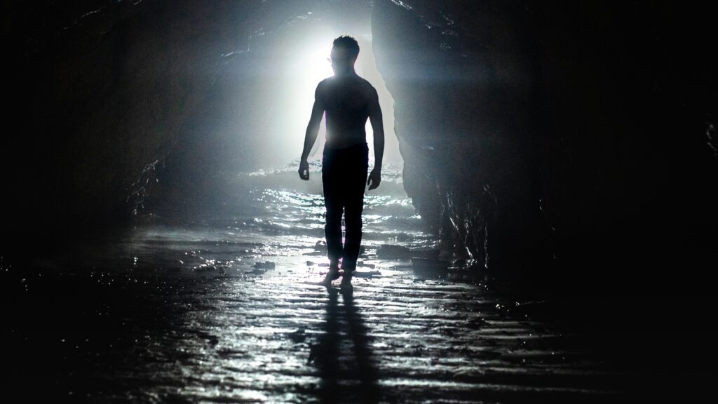 a man is walking through a dark tunnel