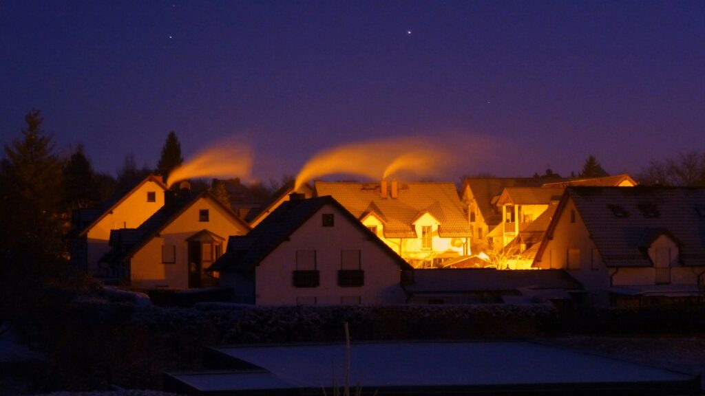 Warm houses with smoke rising into the night sky