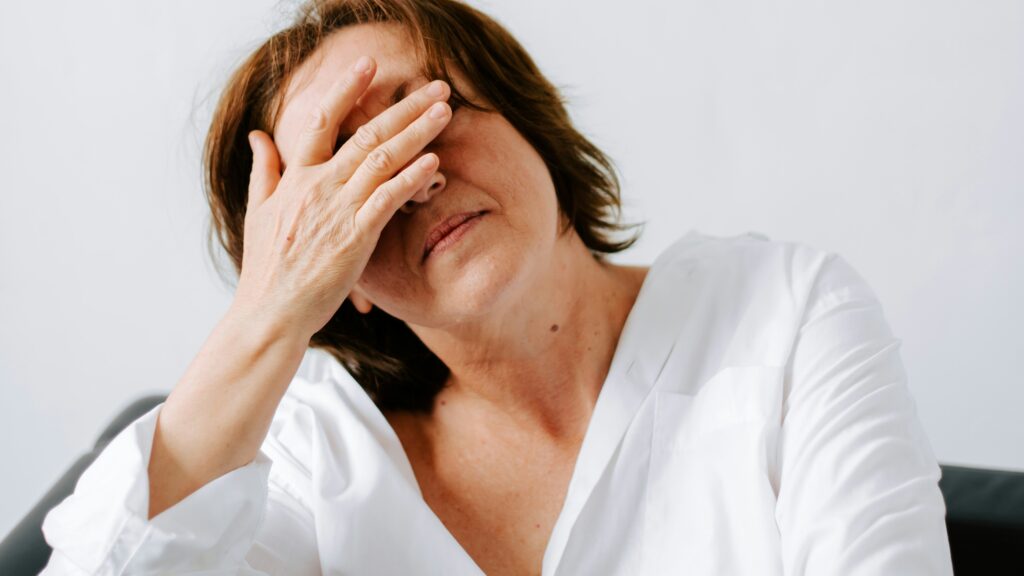 a woman sitting on a couch holding her hands to her face