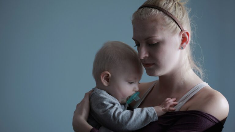 woman carrying baby with pacifier in mouth