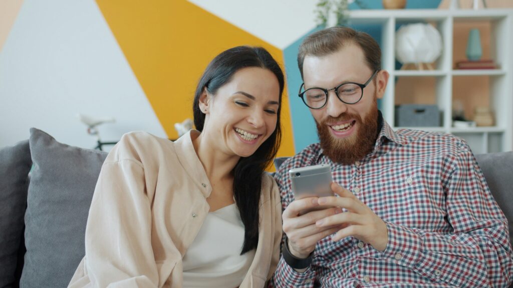 Couple laughing while looking at a smartphone together