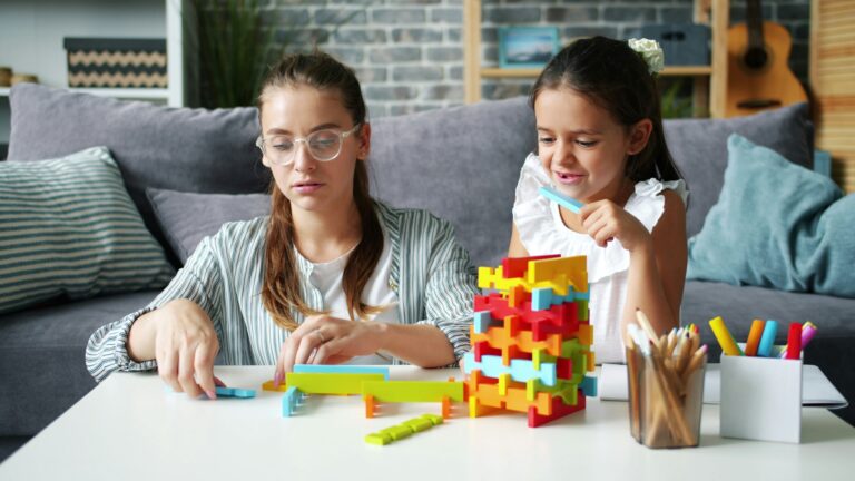 Two girls building with colorful blocks at a table