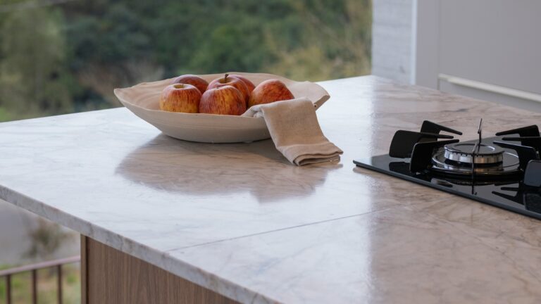 Bowl of apples on marble countertop with stove