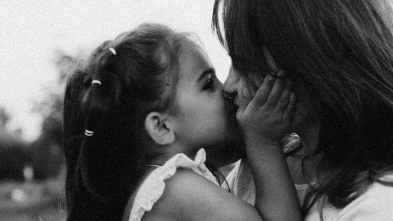 A mother kissing her daughter on the cheek