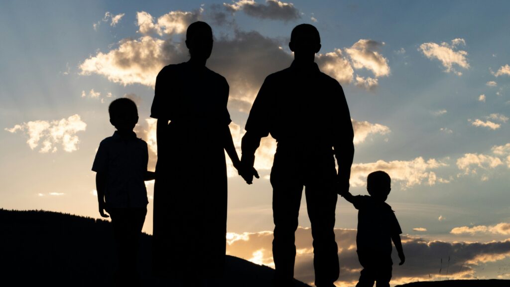a group of people standing on a hill looking at the sunset