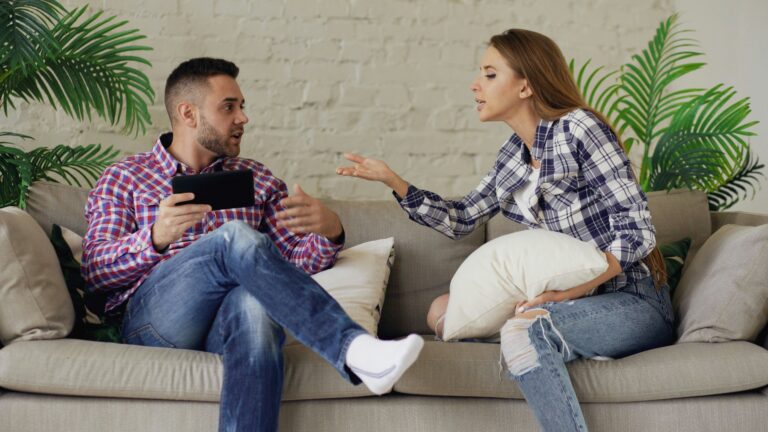 Couple arguing while sitting on a sofa
