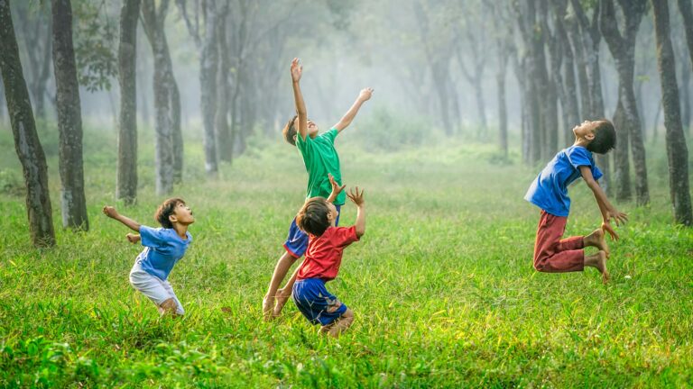 four boy playing ball on green grass