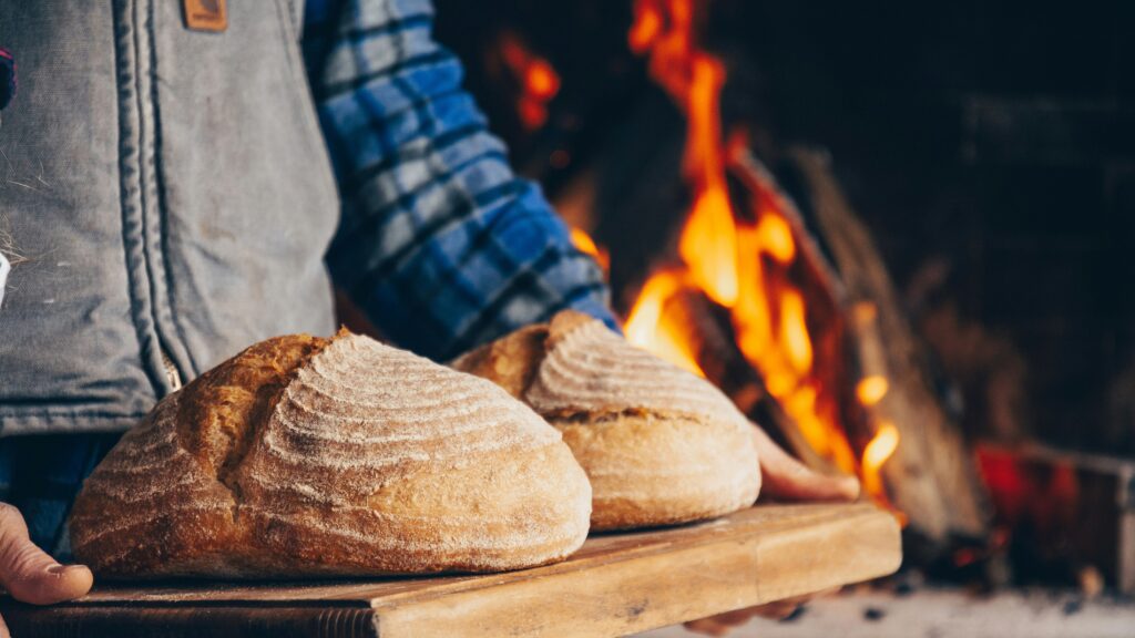 person in blue and white plaid long sleeve shirt holding bread