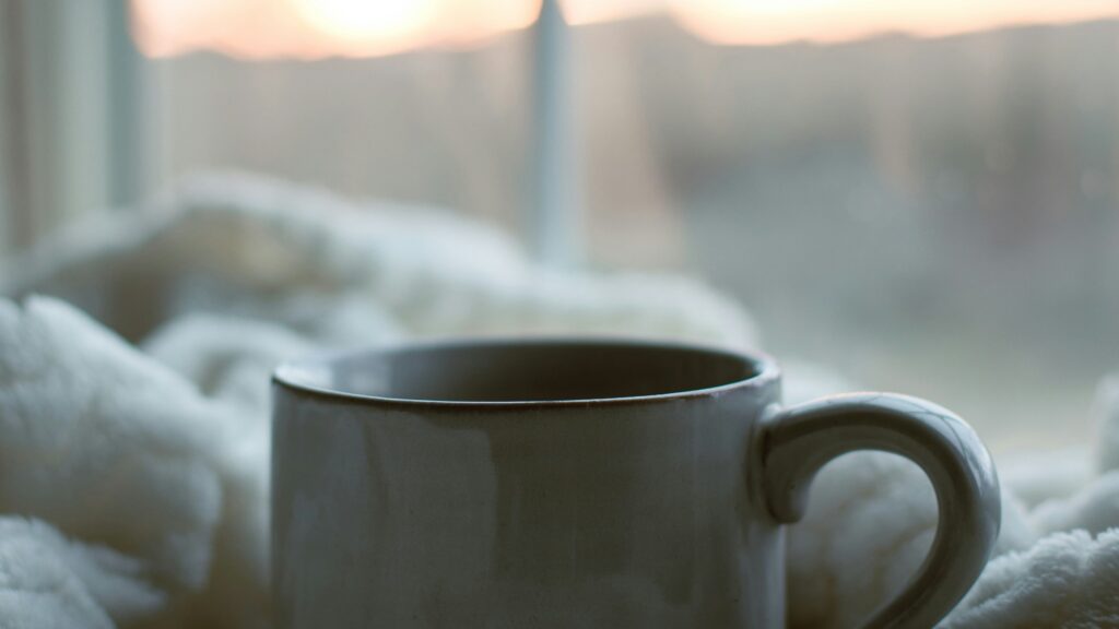 a coffee cup sitting on top of a white blanket