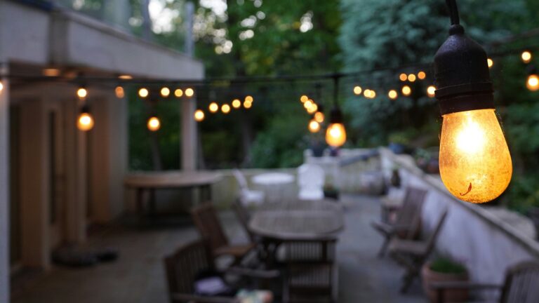String lights illuminate an outdoor patio with tables and chairs