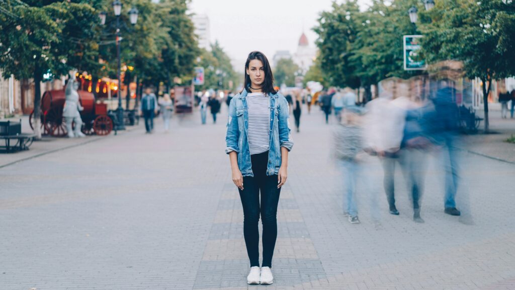 Woman stands still while people blur by