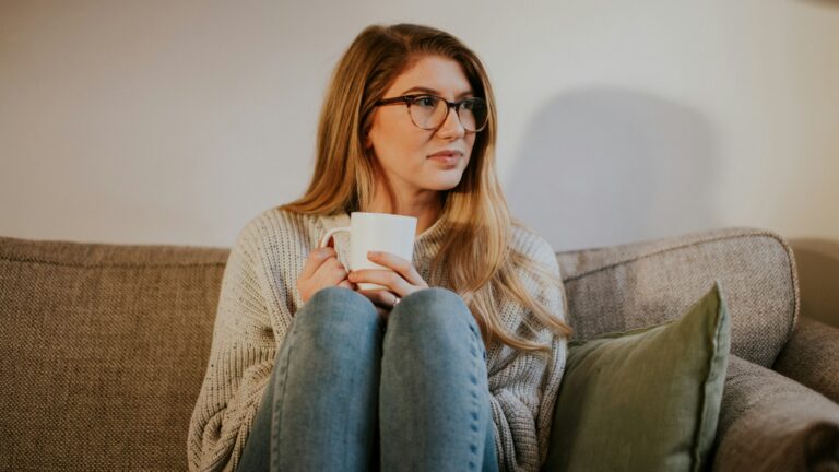 woman in blue denim jeans sitting on gray sofa