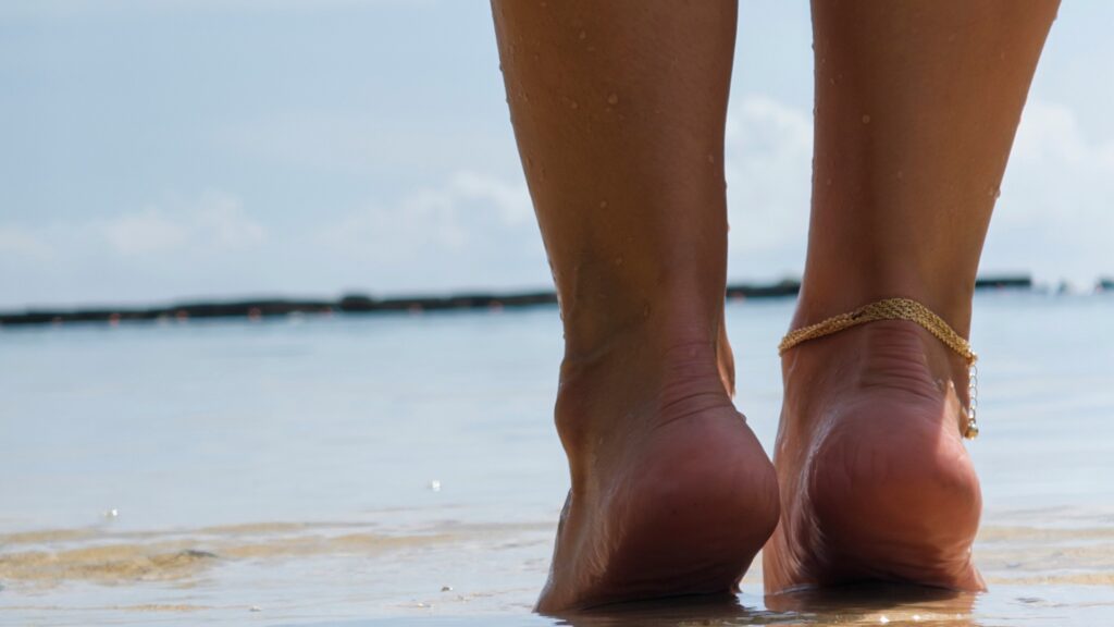 Woman's legs walking on a wet sandy beach