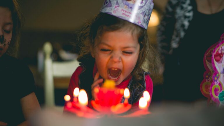 shallow focus photography of toddler blowing cake candles