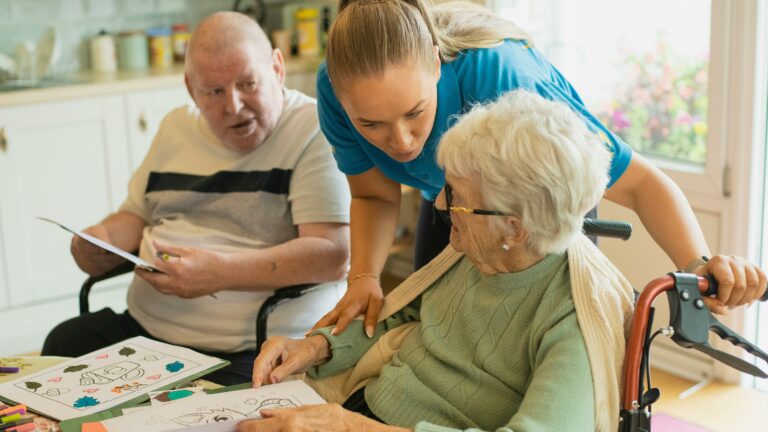 Caregiver assisting elderly couple with coloring