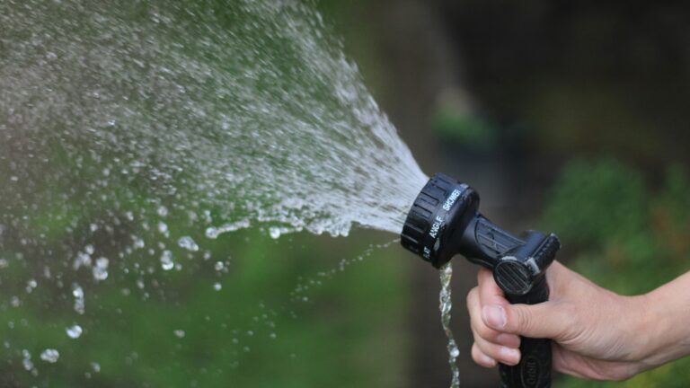 a hand holding a water hose spraying water