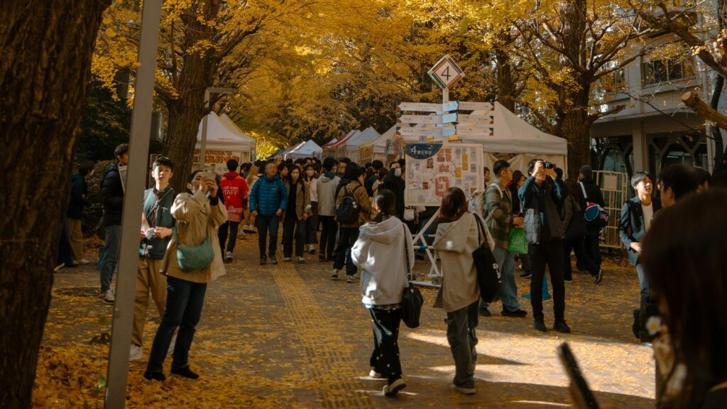 People walking under a path lined with golden ginkgo trees