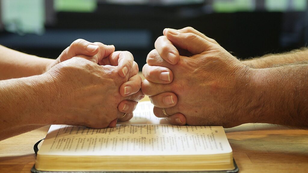 two people holding hands over a book on a table