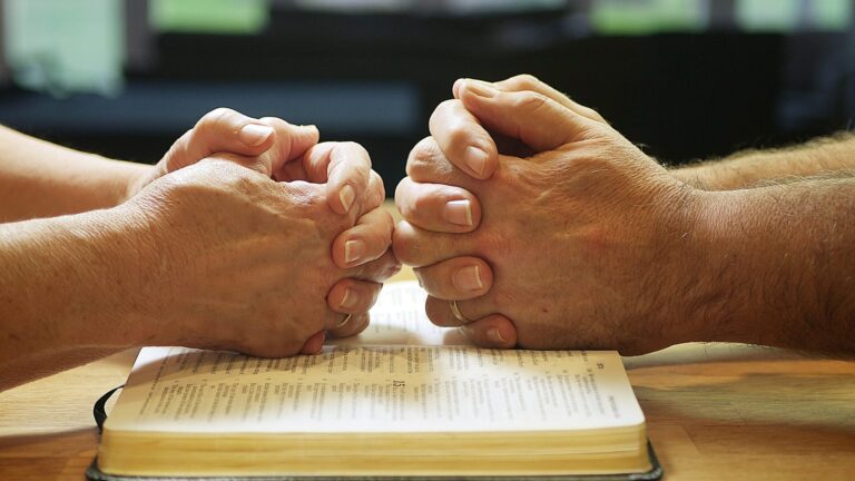 two people holding hands over a book on a table