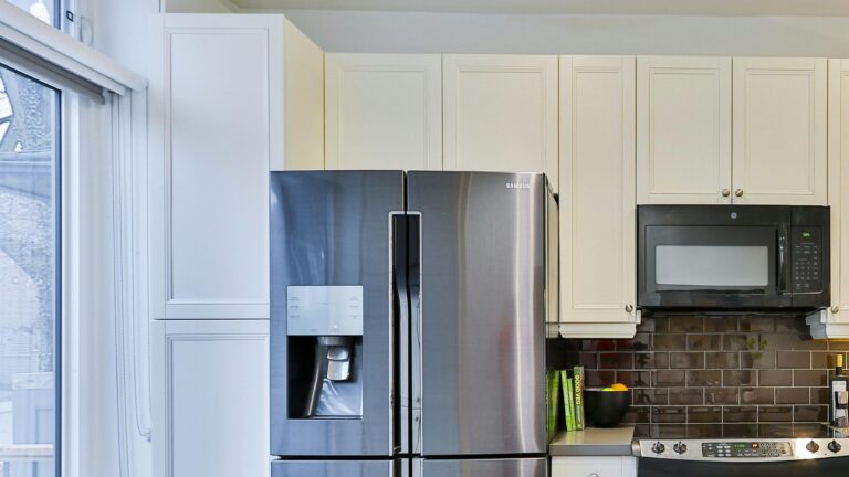 silver french door refrigerator beside white wooden kitchen cabinet