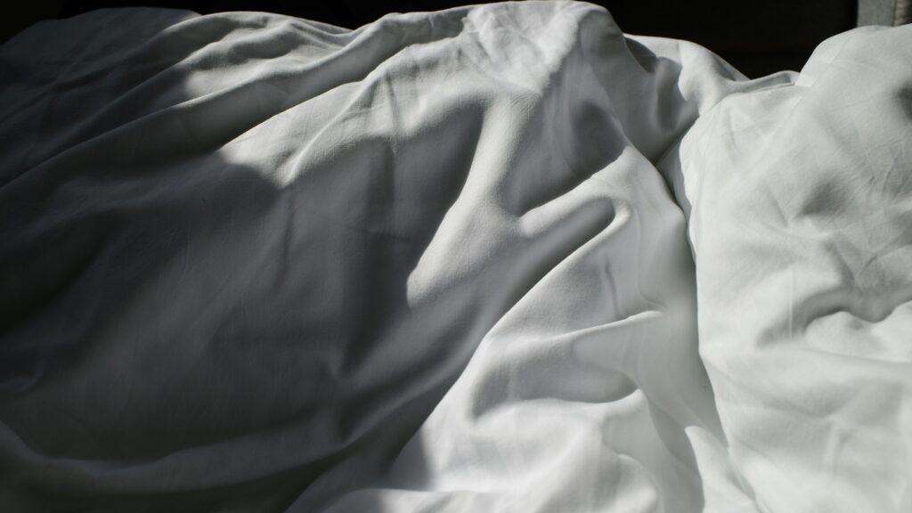 an unmade bed with white sheets and white sheets