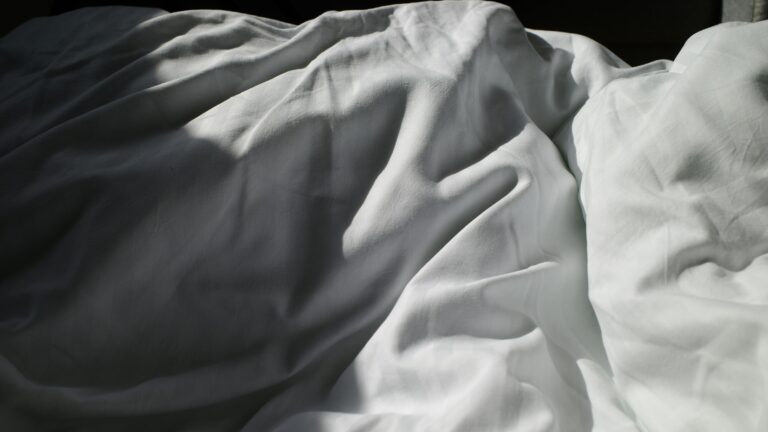 an unmade bed with white sheets and white sheets