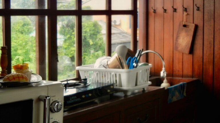 A white microwave and dish rack on a wooden counter in a kitchen
