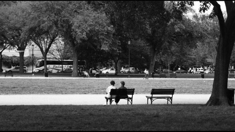 Two people sitting together on a park bench, talking