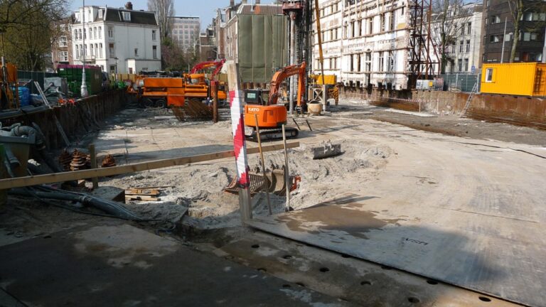 An urban construction site with excavation equipment at the foundation stage of a new building