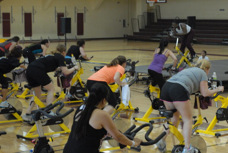 A group of people on stationary bikes in an indoor cycling fitness class