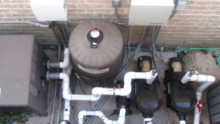 A backyard pool equipment pad with Hayward-branded pumps and a filter housing