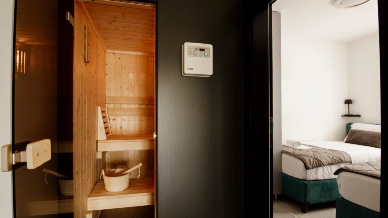 A wood-paneled home sauna interior seen through a glass door