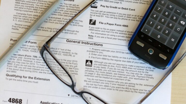 An IRS tax form on a desk with reading glasses and a phone, a generic tax-season scene