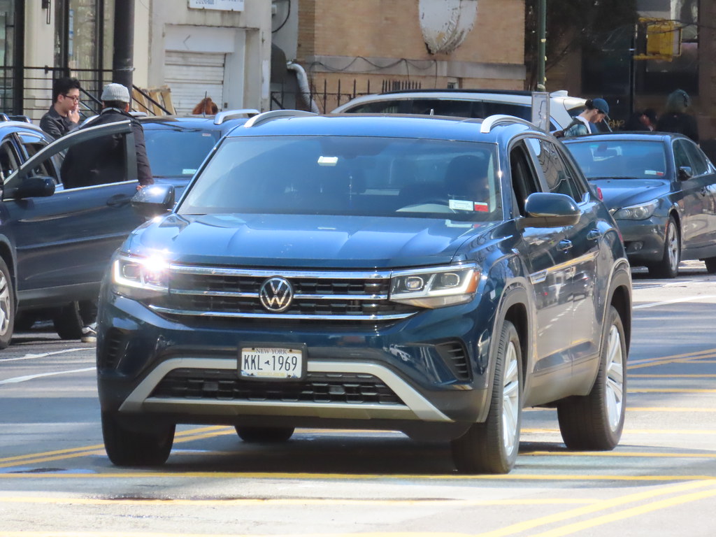 A dark blue Volkswagen Atlas Cross Sport SUV driving on a city street