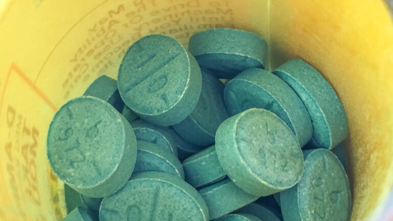 Close-up of blue stimulant pills inside an open prescription bottle