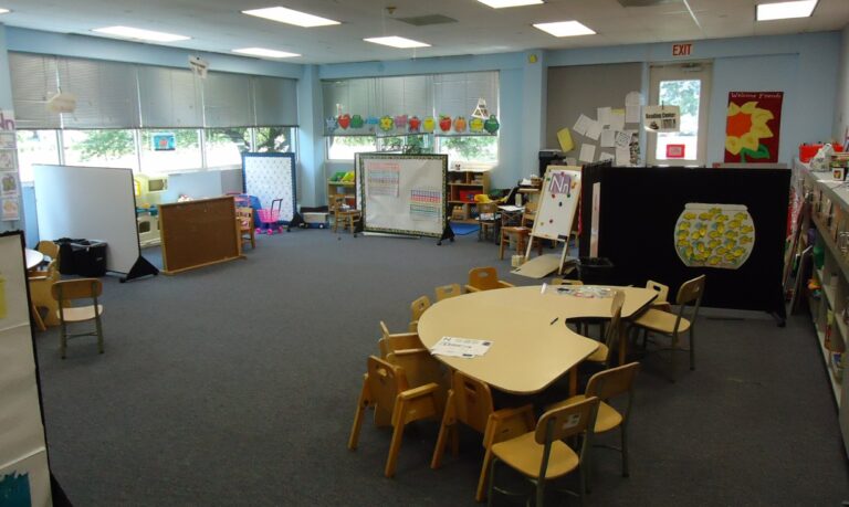 Empty preschool classroom with small chairs and tables set up for young children