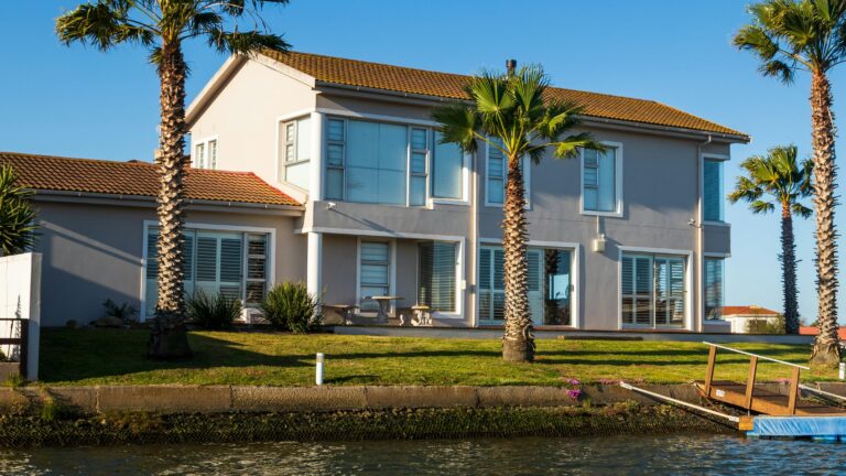 white and brown concrete house beside body of water during daytime