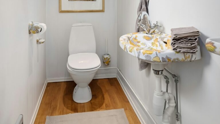 A bathroom with a toilet, sink and mirror