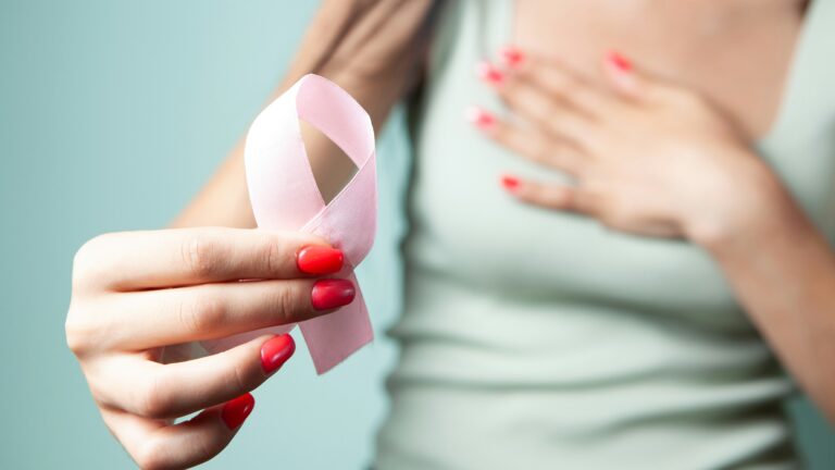 Woman holds pink ribbon for breast cancer awareness